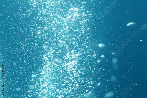 Blue ocean waves from underwater with bubbles. Light rays shining through. Great for backgrounds.