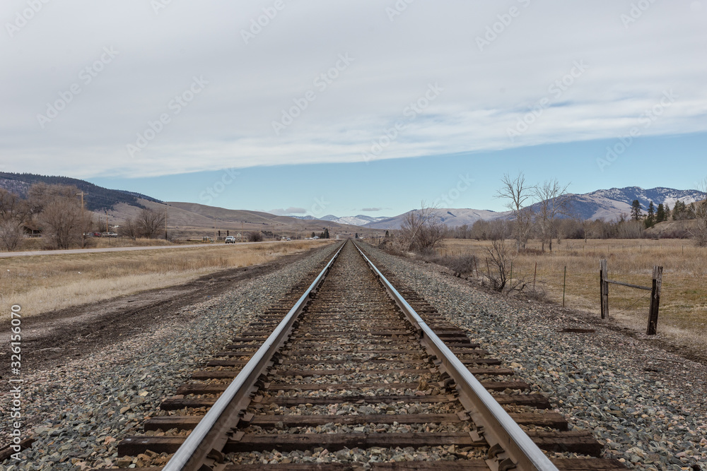 Wide open rolling hill range behind empty railroad tracks on clear day