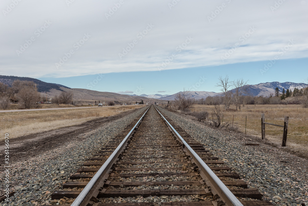 Wide open rolling hill range behind empty railroad tracks on clear day Wide open rolling hill range behind empty railroad tracks on clear day