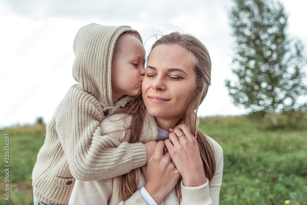 young family, woman mom, hugs child, little son, boy kisses parent, autumn park. Emotions comfort pleasure, smile enjoyment. Love motherhood. Casual clothes hood. Caring for child and parenting. young family, woman mom, hugs child, little son, boy kisses parent, autumn park. Emotions comfort pleasure, smile enjoyment. Love motherhood. Casual clothes hood. Caring for child and parenting.