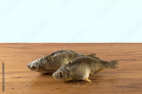 Dried fish on the table. Salty dry river fish on a white background. Dead dry salty fish - snack to beer. Isolated on white. . photo