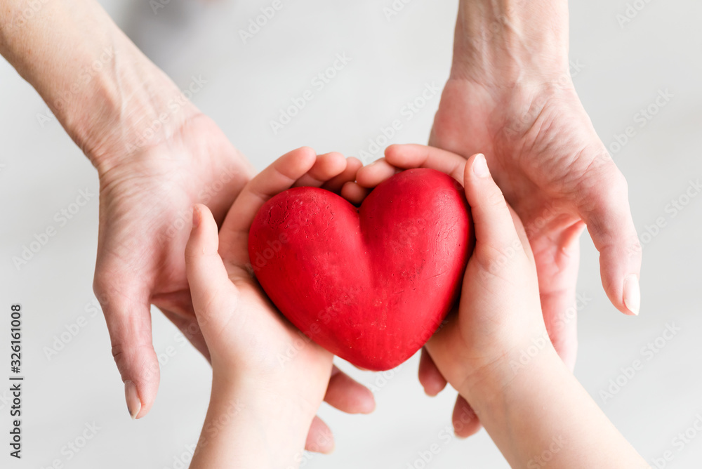 Childs hands and older woman hands holding heart. Concept o love, share and care. Care for elderly concept. Childs hands and older woman hands holding heart. Concept o love, share and care. Care for elderly concept.