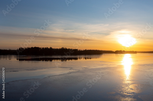 Amazing winter sunset in Finland. Cold afternoon in February  reflecting water and icy surface. Wintry landscape wallpaper  copy space.