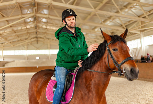 man jockey sitting on horse, horseback training on manege, lesson for jockey in equestrian school or club, pet animal
