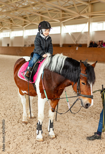 young jockey boy riding horse, horseback training on manege, lesson for young jockey in equestrian school or club, pet animal