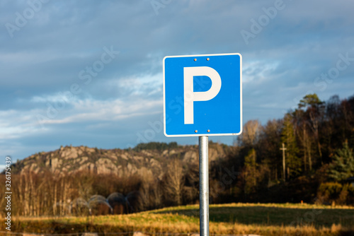 Parking allowed sign. Trees and mountains in the background.