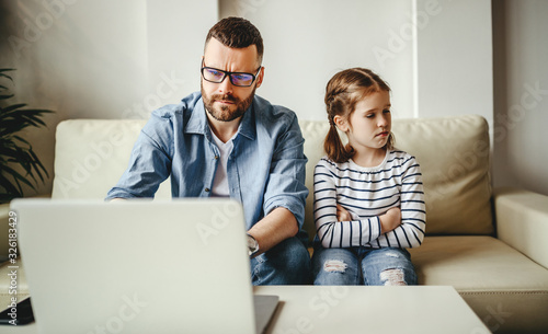Fotografia family a businessman father working at a computer and his child daughter  offended angry