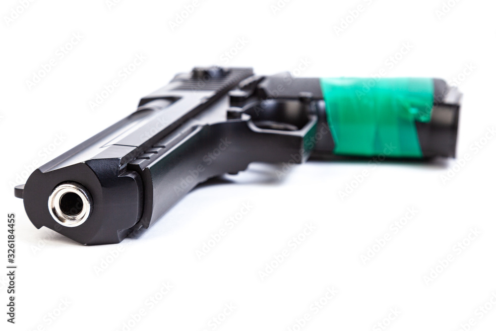 Black steel pistol with a handle wrapped in green electrical tape on a white isolated background turned by the barrel towards the viewer
