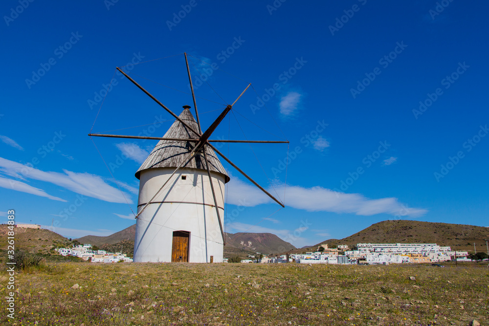 traditional windmill and behind the village of El Pozo de los Frailes, windmill traditional in Spain, Pozo de los Frailes, province of Almeria, windmill under blue sky traditional windmill and behind the village of El Pozo de los Frailes, windmill traditional in Spain, Pozo de los Frailes, province of Almeria, windmill under blue sky