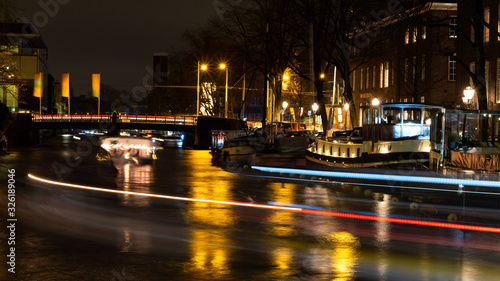Amsterdam Canal at silent night with moving boats © Arda
