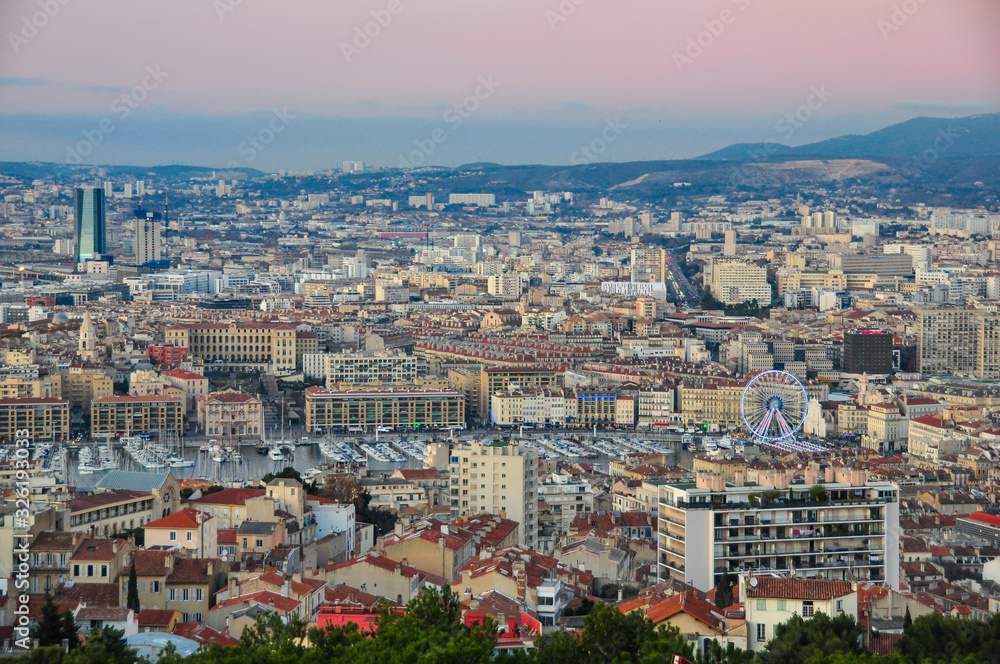 Panoramic view on the well known Vieux Port of the city of Marseille with the town hall and the ferris wheel on a pink evening at blue hour