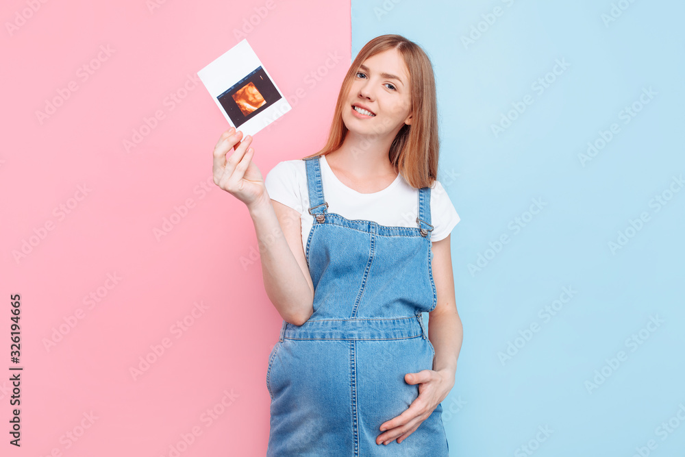 Young attractive pregnant woman in denim overalls with ultrasound scan photo Young attractive pregnant woman in denim overalls with ultrasound scan photo