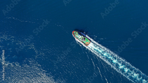 Aerial drone ultra wide top down photo of tug assisting boat cruising near Asian destination port © aerial-drone