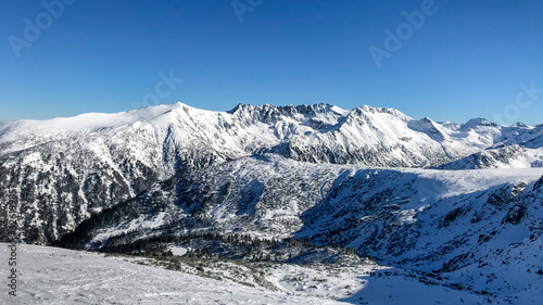 Snow covered mountains in winter.
Great View On The Snowy Mountain Peaks and beautiful blue cloudy sky.