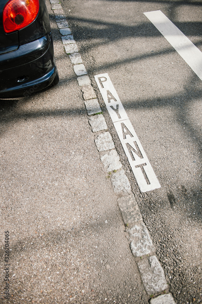Fototapeta premium Payant przetłumaczone jako Płatny parking i część pojazdu w centralnej części francuskiego miastaa
