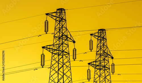 lectric power industry. Transmission towers or electricity pylons with golden sky background photo