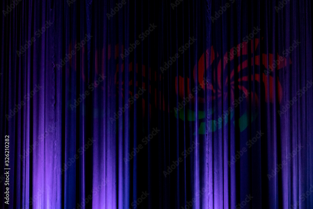 Black backdrop with blue lights with a red and green hieroglyph in the middle in a city theater