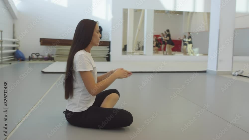 Tracking slowmo shot of young female cheer coach sitting on floor and teaching teen and preteen girls practicing lifting cheerleading stunt Tracking slowmo shot of young female cheer coach sitting on floor and teaching teen and preteen girls practicing lifting cheerleading stunt