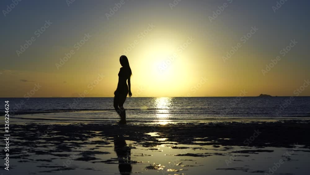 Happy young woman dancing on a tropical beach during sunset. Dance of caucasian girl near sea water Happy young woman dancing on a tropical beach during sunset. Dance of caucasian girl near sea water