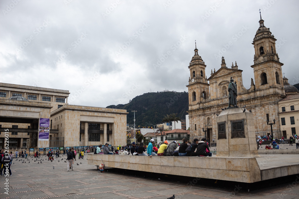People in Bolivar Square in middle of Downtown. Catedral Primada at right and Palacio de Justicia left of the capture Monserrate church at background.