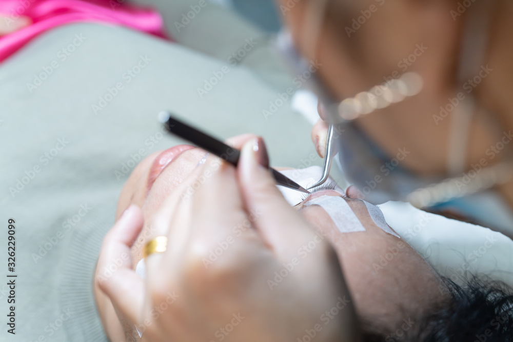 Procedure of eyelashes extension in salon close up - with long eyelashes on Eyelash extension