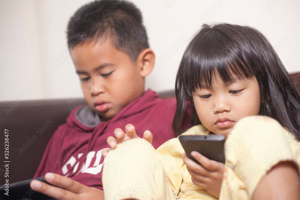 Little kids sister and brother siblings plays on gadget smart phone Little kids sister and brother siblings plays on gadget smart phone