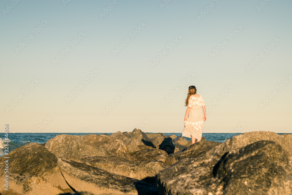 Girl Standing on Rocks with Ocean Horizon in Background