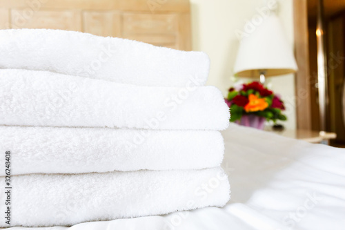 Fototapeta Naklejka Na Ścianę i Meble -  Fresh white towel pile in the upscale hotel room. Being alone, getaway, staycation, digital detox, trip, vacation concepts. Horizontal