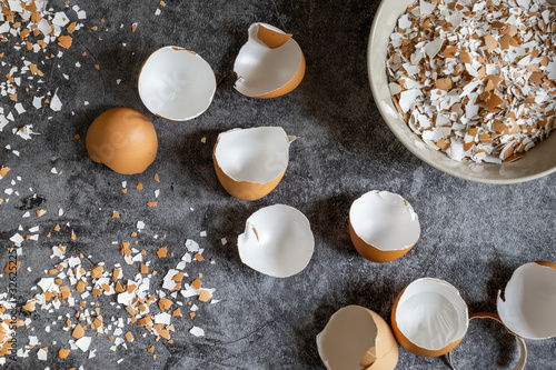 Top view of cracked eggshells and grinded eggshells on dark stone table
