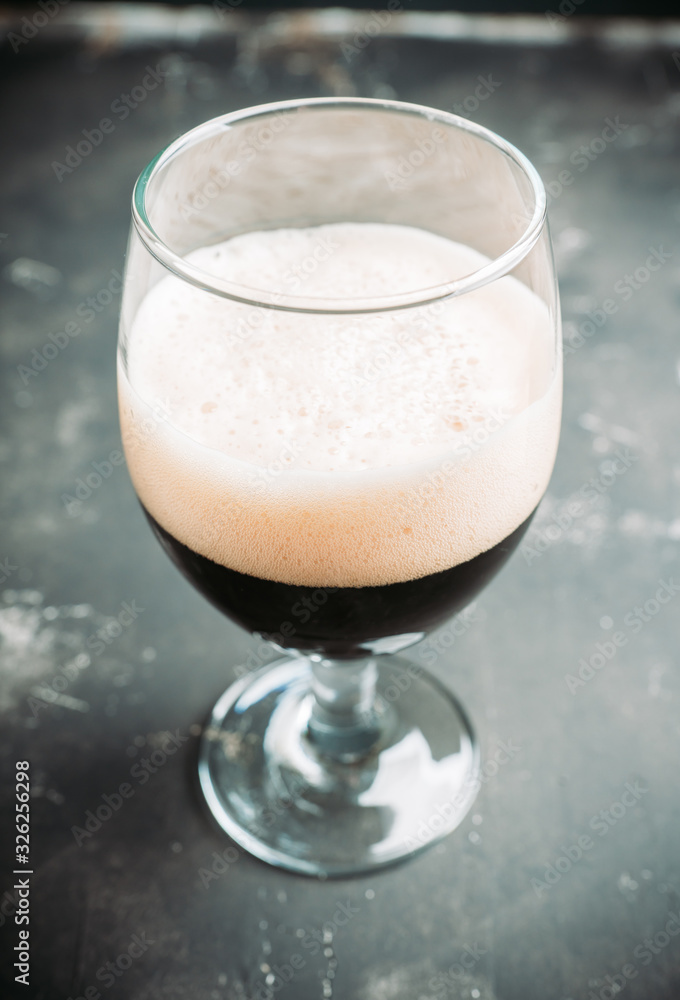 Freshly brewed dark beer on the black rustic background. Selective focus. Shallow depth of field. Freshly brewed dark beer on the black rustic background. Selective focus. Shallow depth of field.