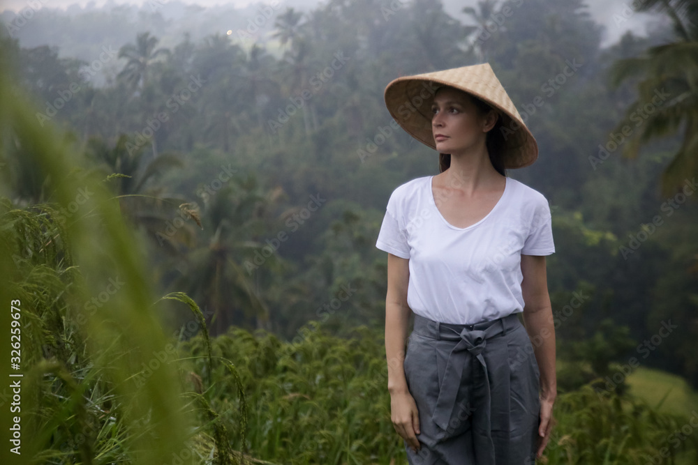 Woman wearing traditionl bamboo hat on the rice field terrace	