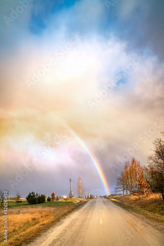 Early spring landscape with dramatic sky, rainbow and road lines