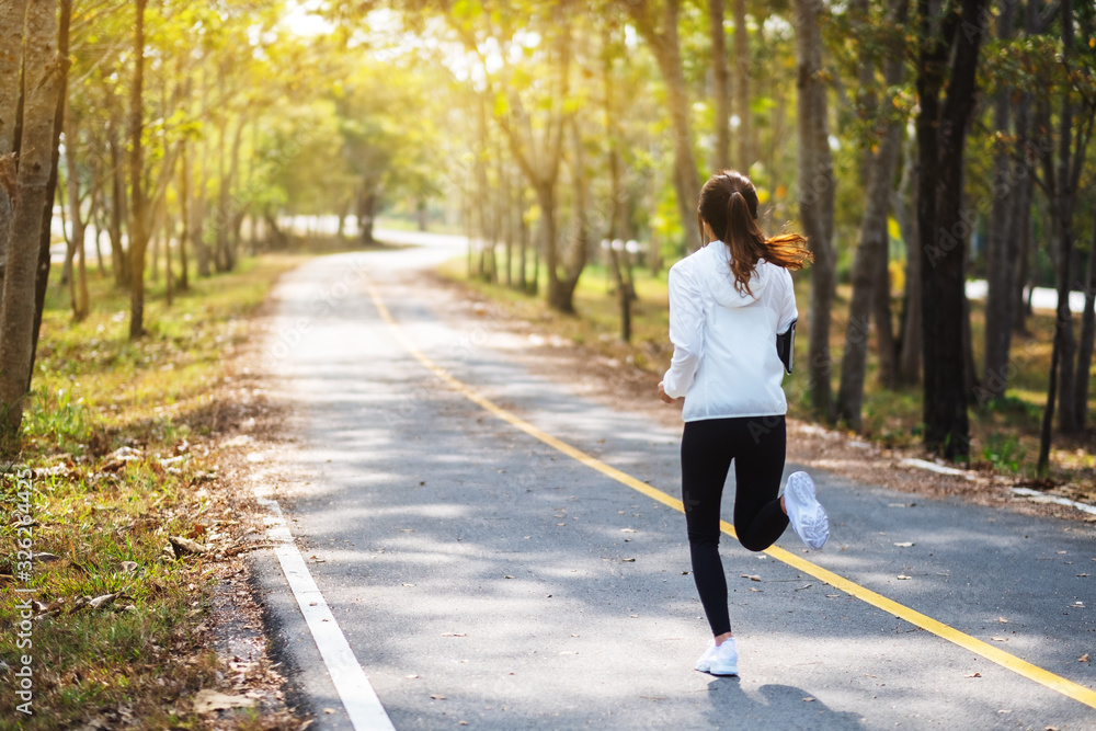 Rear view image of a young asian woman jogging in city park in the morning Rear view image of a young asian woman jogging in city park in the morning