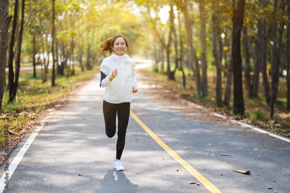 A young beautiful asian woman jogging in city park in the morning A young beautiful asian woman jogging in city park in the morning