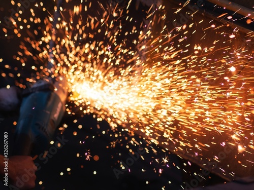 worker grinding cutting metal sheet with grinder machine overwrites the master of welding seams angle grinder and sparks. Electric grinder in the industrial workshop. photo