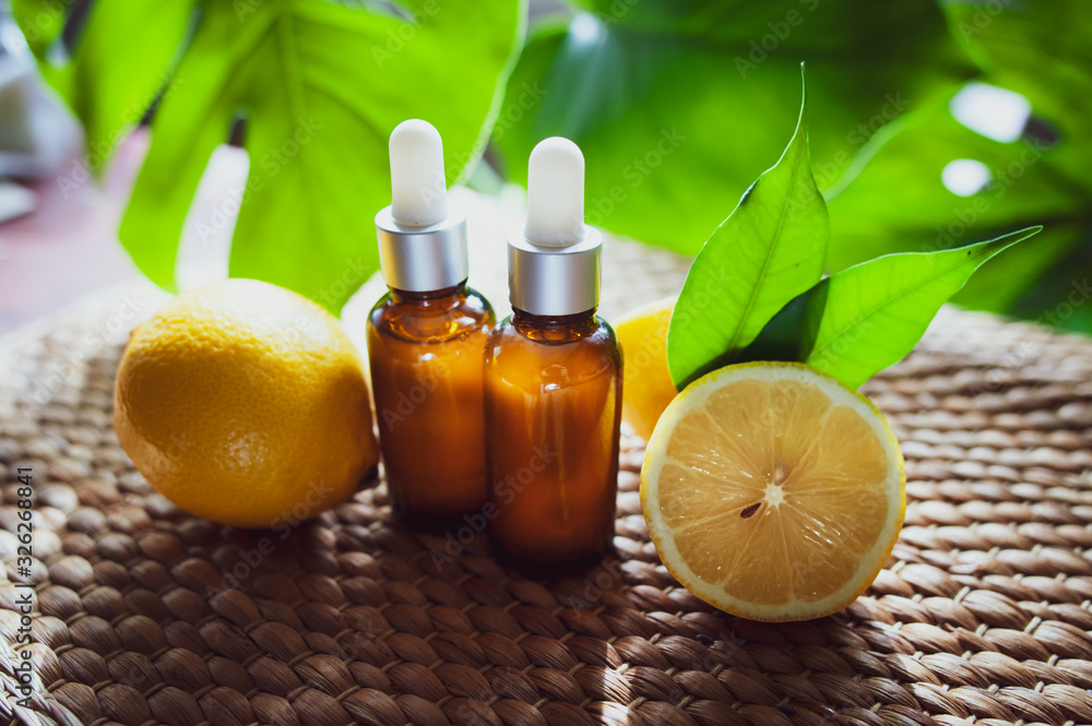 Φωτογραφία Bottles with lemon oil, fresh  fruit whole and half on a natural tropical background