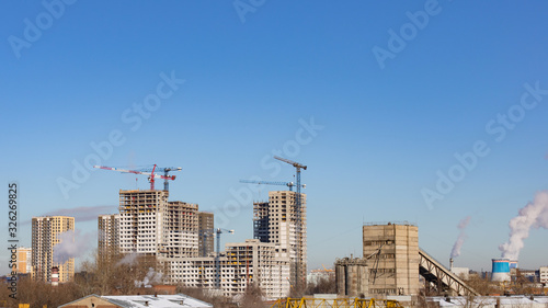 The construction of a modern multi-storey residential area, a construction crane erects a skyscraper with residential apartments. Building new districts, renovation