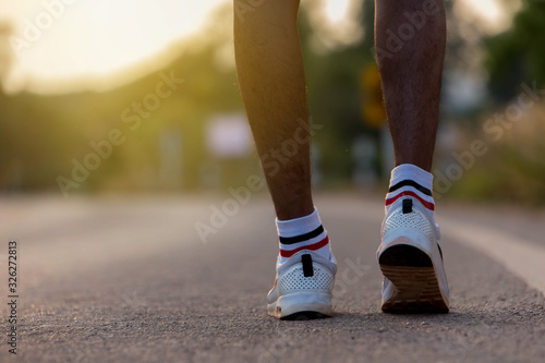 Runner feet running on road closeup on shoe. man fitness sunrise jog workout welness concep