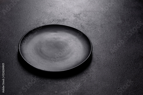 Empty black plate over dark stone background with free space
