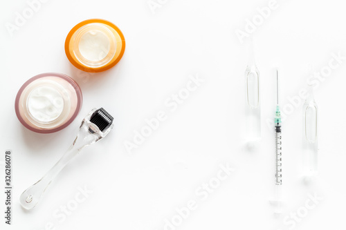 Dermatologist work desk with tools. Dermaroller, syringe, ampoule on white background top-down flat lay copy space
