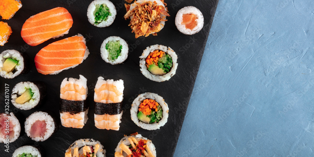 Large sushi set panorama with copy space. An assortment of various maki, nigiri and rolls Large sushi set panorama with copy space. An assortment of various maki, nigiri and rolls