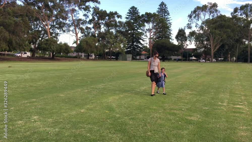 Mothers and young daughter walking home together after school.Motherhood concept. Real people. Copy space Mothers and young daughter walking home together after school.Motherhood concept. Real people. Copy space