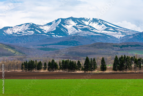 Rural landscapes. Rolling mountain range, farmland field and blue sky with white clouds in a beautiful sunny day in high latitude country springtime