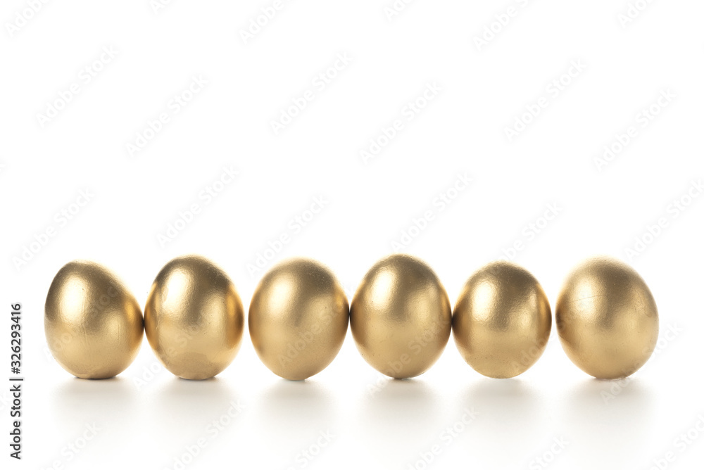 eggs painted with gold paint stand in a row on a white background. place for text on top. eggs painted with gold paint stand in a row on a white background. place for text on top.