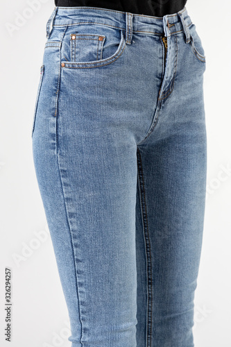 Fototapeta Naklejka Na Ścianę i Meble -  girl in jeans shows off jeans on white background close up, blue jeans