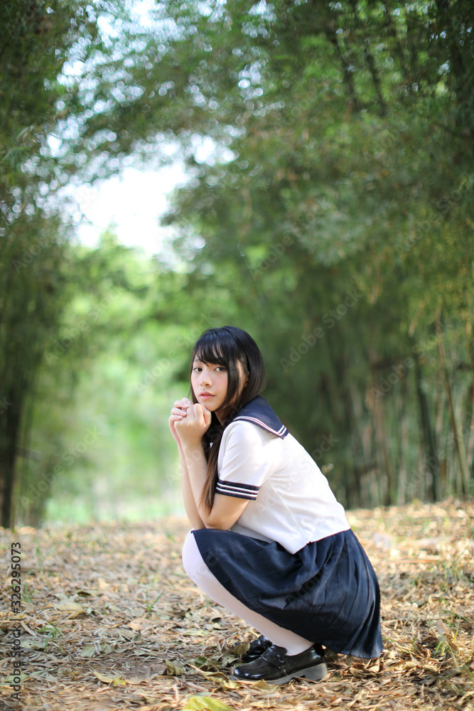 Portrait of beautiful Asian japanese high school girl uniform looking with bamboo forest background Portrait of beautiful Asian japanese high school girl uniform looking with bamboo forest background