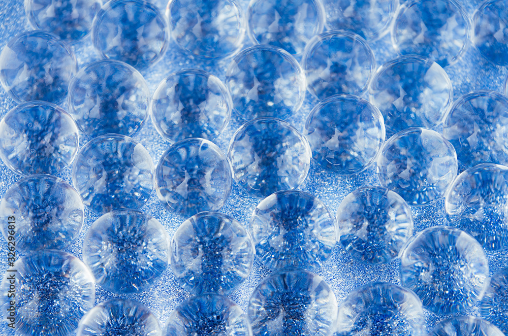 Naklejka premium Abstract blue background with transparent glass balls on glitter backdrop, texture, pattern.