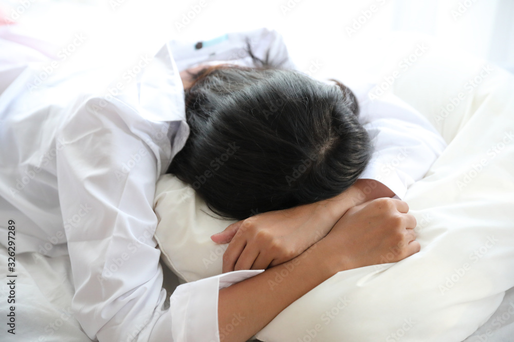 Asian woman lazy sleep waking up on bed with clock in white bedroom Asian woman lazy sleep waking up on bed with clock in white bedroom