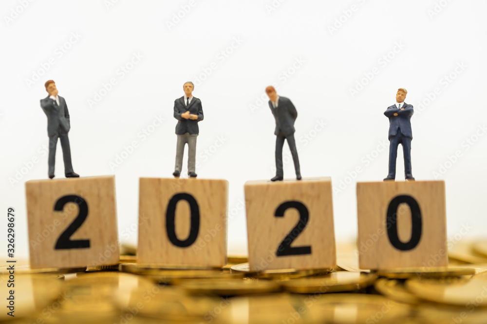 2020 New year, Business, Money, Finance and Saving concept. Closeup of miniature people figure on wooden block number on golden coins and white background with copy space text. 2020 New year, Business, Money, Finance and Saving concept. Closeup of miniature people figure on wooden block number on golden coins and white background with copy space text.