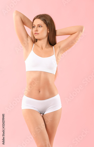 Beautiful young woman in underwear on color background